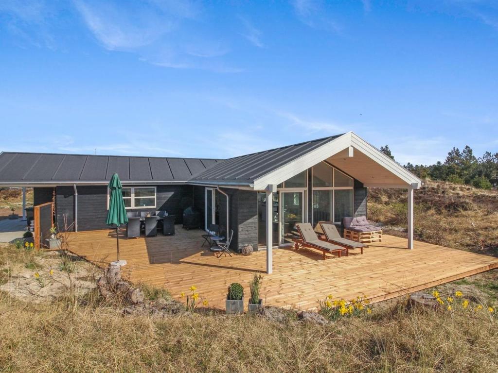 a house with a wooden deck with a roof at Holiday Home Minke - 2-2km from the sea in Western Jutland in Bolilmark