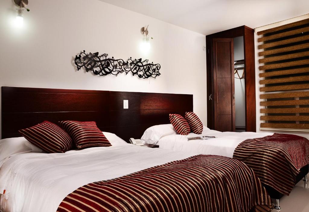 a bedroom with two beds with red and white pillows at Hotel Parque 63 in Bogotá