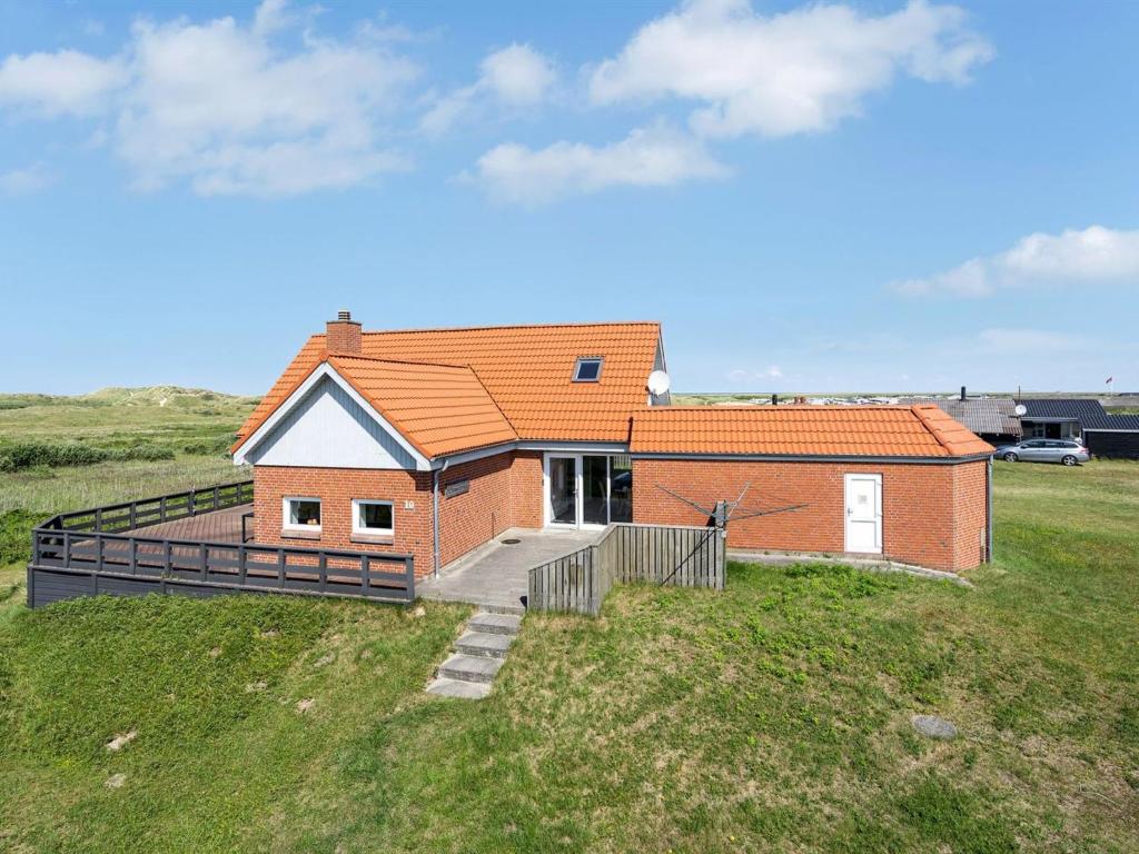 uma casa numa colina relvada com um quintal em Holiday Home Helfrida - 350m from the sea in Western Jutland by Interhome em Lakolk