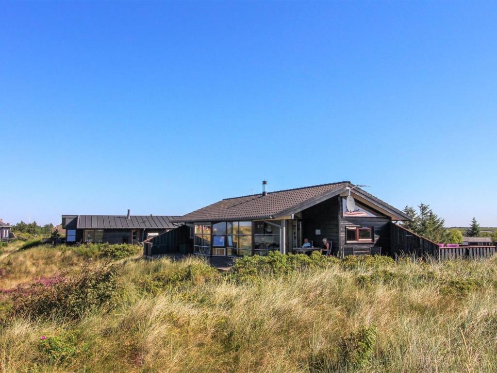 uma casa no topo de uma colina relvada em Holiday Home Alim - 300m from the sea in Western Jutland by Interhome em Lakolk