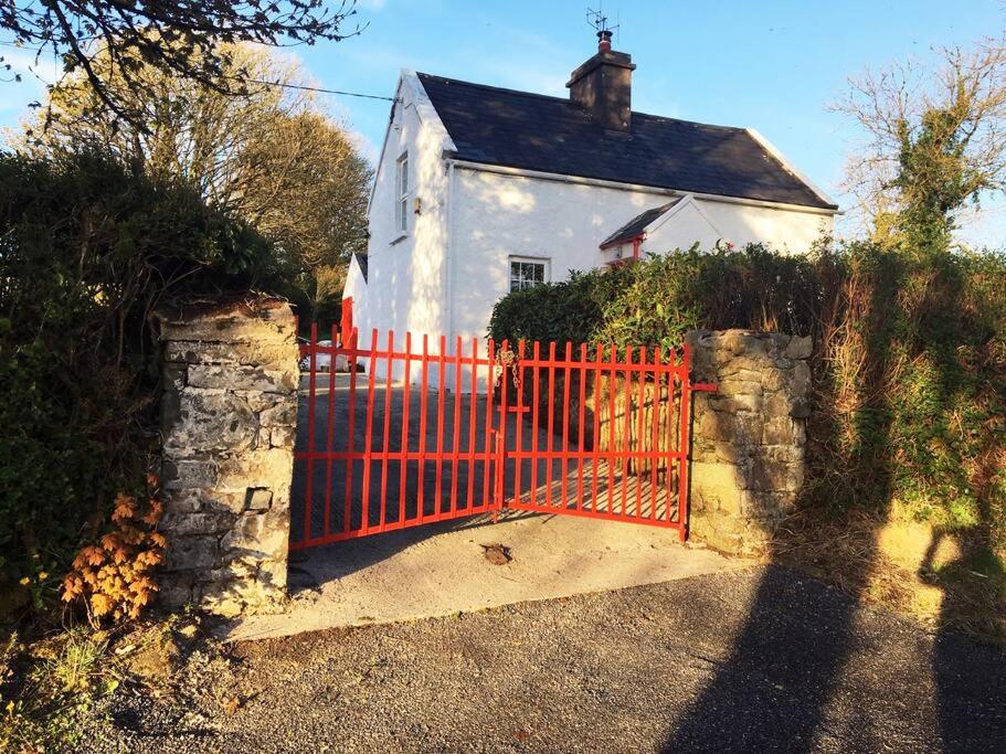 ein rotes Tor vor einem weißen Haus in der Unterkunft Maggie's Cottage in Thurles