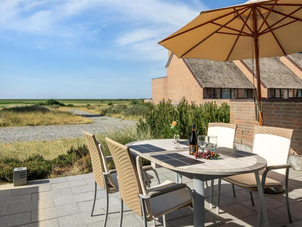 un patio con mesa, sillas y sombrilla en Apartment Helgo - 250m from the sea in Western Jutland by Interhome en Sønderby