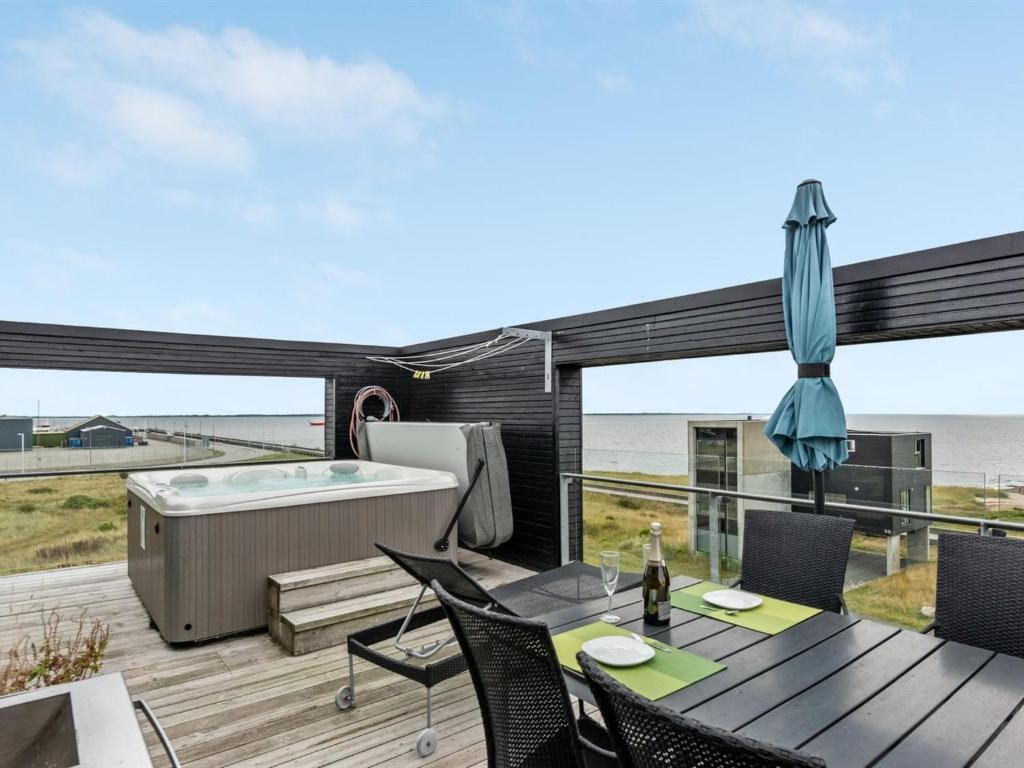 a deck with a hot tub and a table and chairs at Holiday Home Leto - 2km from the sea in Western Jutland in Havneby