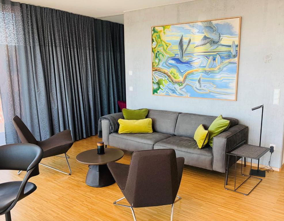 a living room with a gray couch and chairs at Trilogie am See Wohnung Taube in Stetten