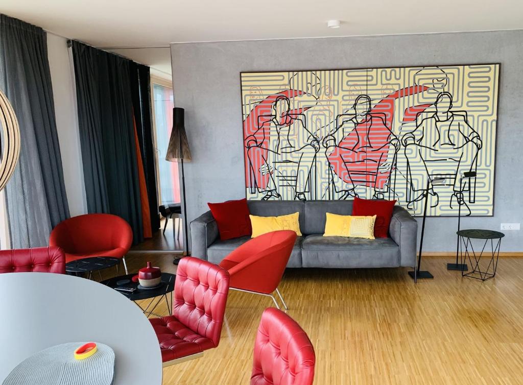 a living room with a couch and red chairs at Trilogie am See Wohnung Schmetterling in Stetten