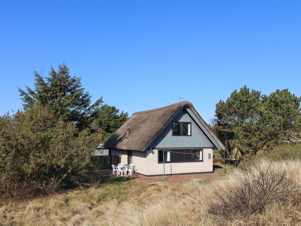 una pequeña casa blanca con techo de paja en Holiday Home Pisana - 400m from the sea in Western Jutland by Interhome, en Vejers Strand