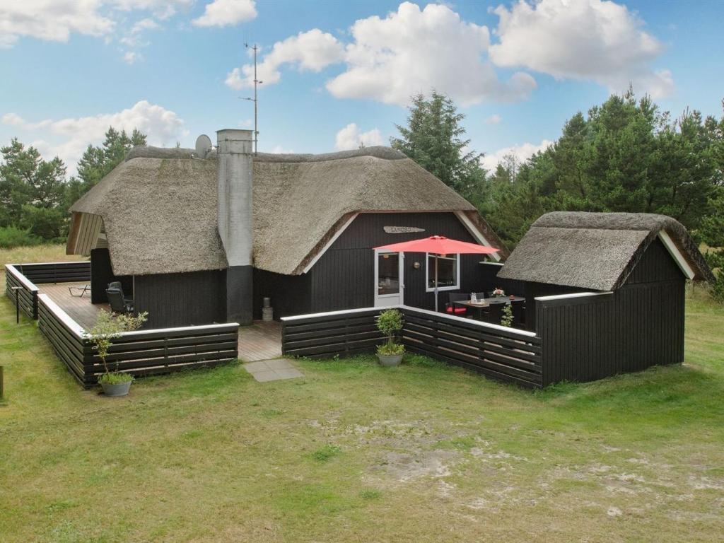 une grande maison noire avec un toit de chaume dans l'établissement Holiday Home Patrik - 1-4km from the sea in Western Jutland by Interhome, à Blåvand