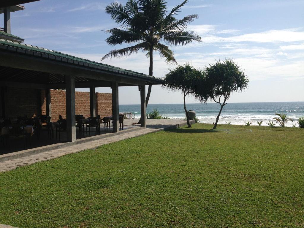 a restaurant on the beach with palm trees and the ocean at The Beach Cabanas Retreat & Spa in Koggala