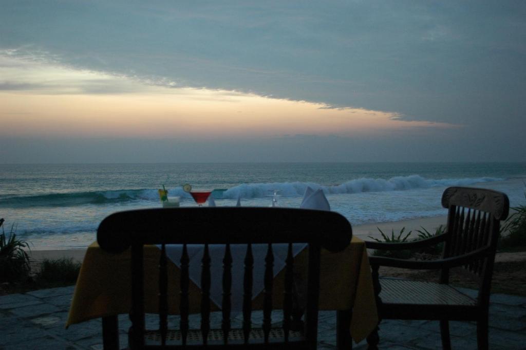 a table and chairs on the beach at sunset at The Beach Cabanas Retreat & Spa in Koggala
