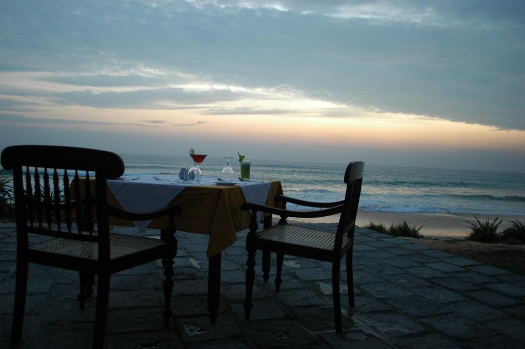 a table with two chairs and the ocean at sunset at The Beach Cabanas Retreat & Spa in Koggala