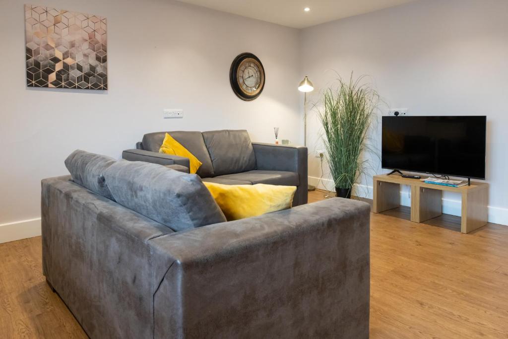 a living room with a couch and a flat screen tv at James Charles Apartments in Milton Keynes