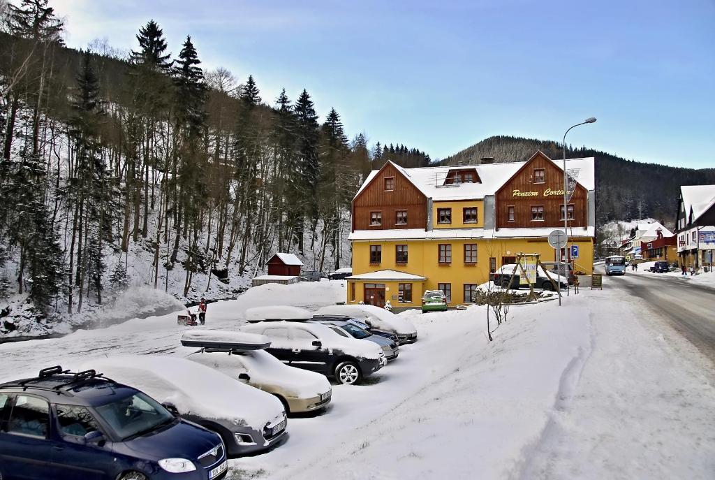 eine Gruppe von Autos, die im Schnee vor einem Haus geparkt sind in der Unterkunft Pension Cortina in Pec pod Sněžkou