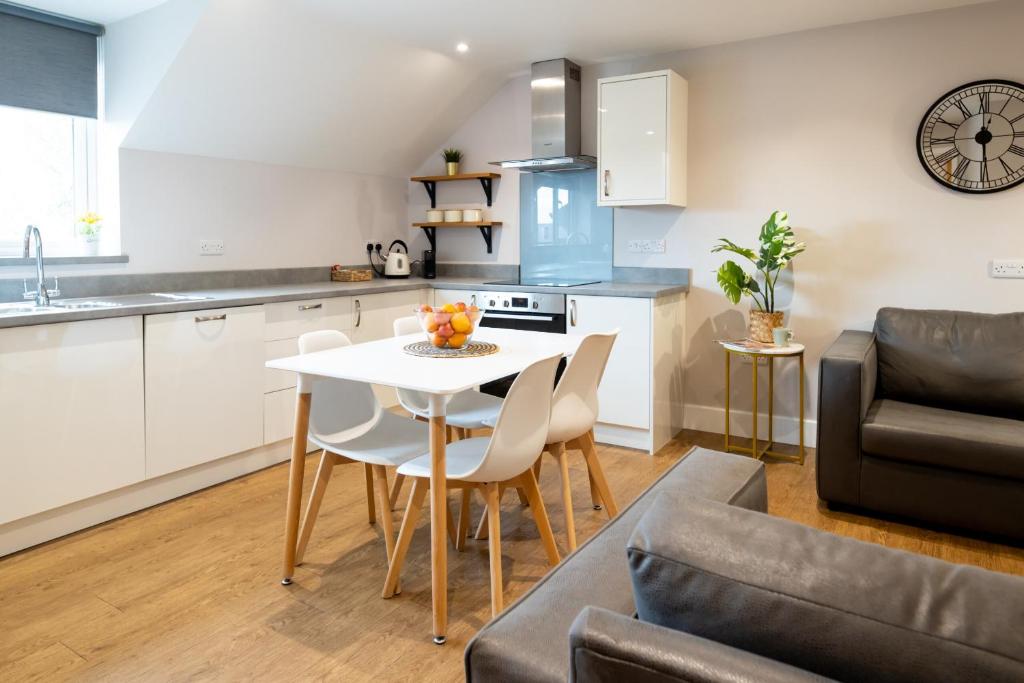 cocina y sala de estar con mesa blanca y sillas en James Charles Apartments, en Bletchley