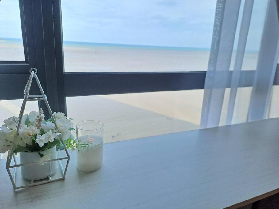 einen Tisch mit einer Vase aus Blumen und einem Fenster in der Unterkunft Best moments Studio Seaview in Kuantan