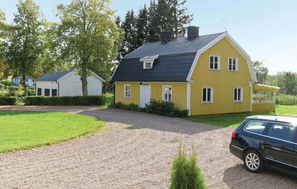 una casa amarilla con un coche aparcado delante de ella en Amazing Home In Tidaholm With Kitchen en Tidaholm