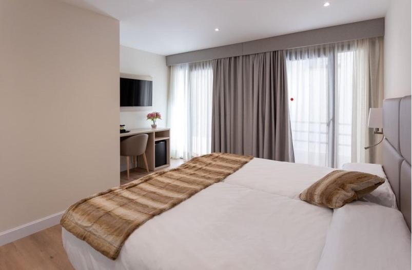 a bedroom with a large white bed in front of a window at Hotel SAIOLA in Camprodon