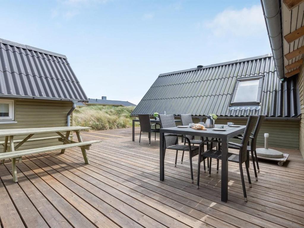 eine Holzterrasse mit Tischen und Stühlen auf einem Haus in der Unterkunft Holiday Home Hinz - from the sea by Interhome in Ringkøbing