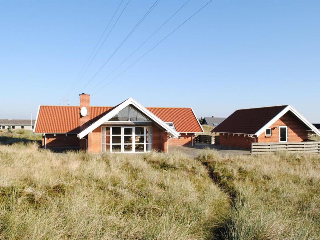 a house on top of a grassy hill at Holiday Home Drusilla - 800m from the sea in Western Jutland by Interhome in Hvide Sande