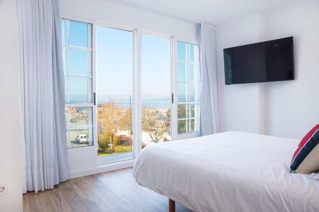 Un dormitorio con una cama y una ventana grande. en P2 O Grove Centro con vistas al mar y parking, en O Grove
