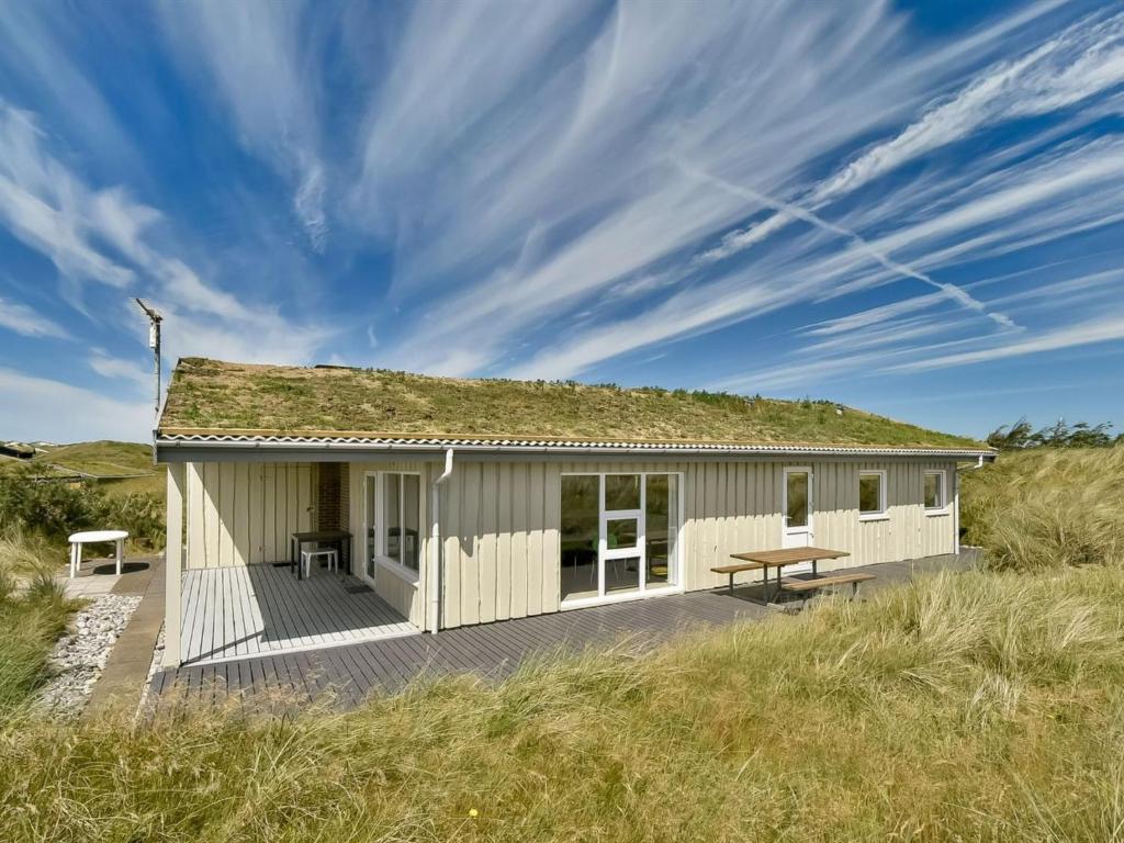 a small white house with a grass roof at Holiday Home Gundine - from the sea in Western Jutland by Interhome in Ringkøbing