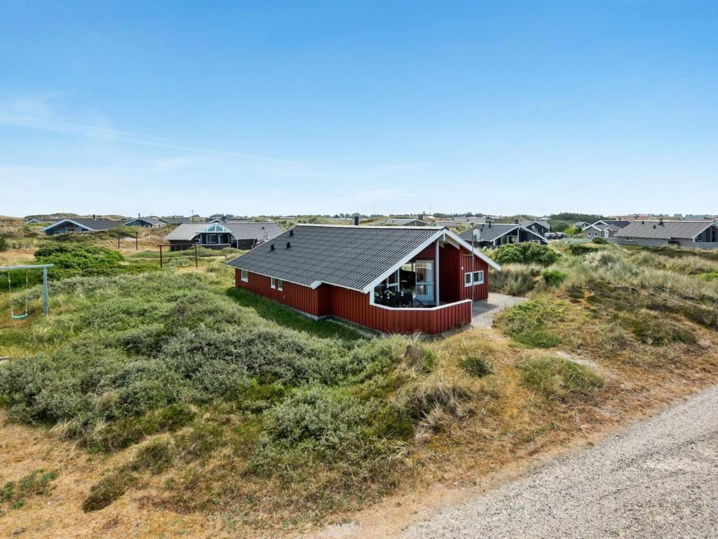 a red house in the middle of a field at Holiday Home Tuure - from the sea in Western Jutland by Interhome in Bjerregård