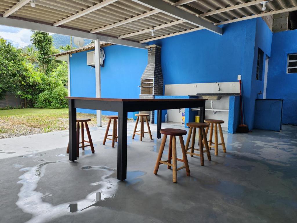 une table et des tabourets devant un mur bleu dans l'établissement Cantinho residencial, à Maresias