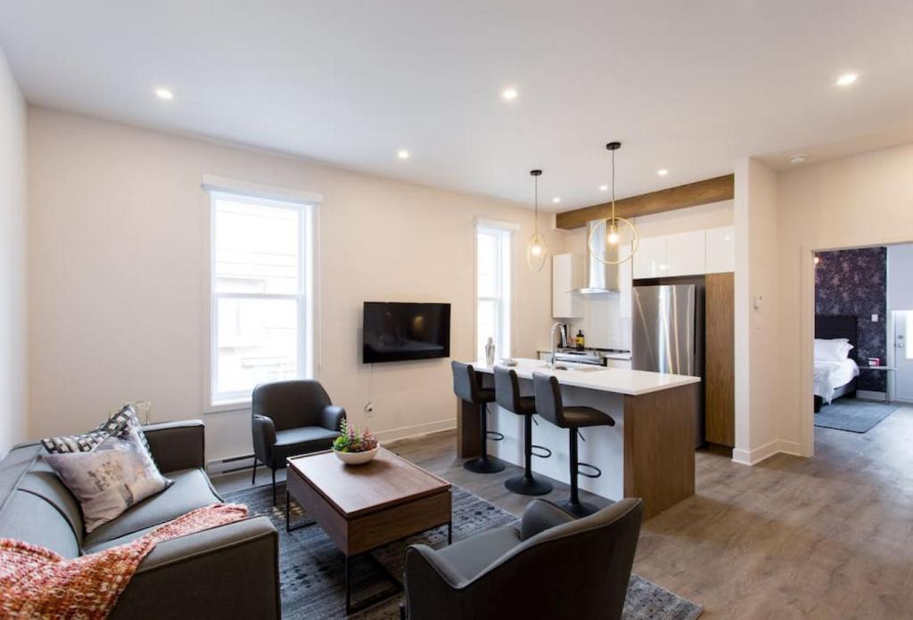 a living room with a couch and a table in a room at Brand New Light filled Mile End Flat by Denstays in Montréal