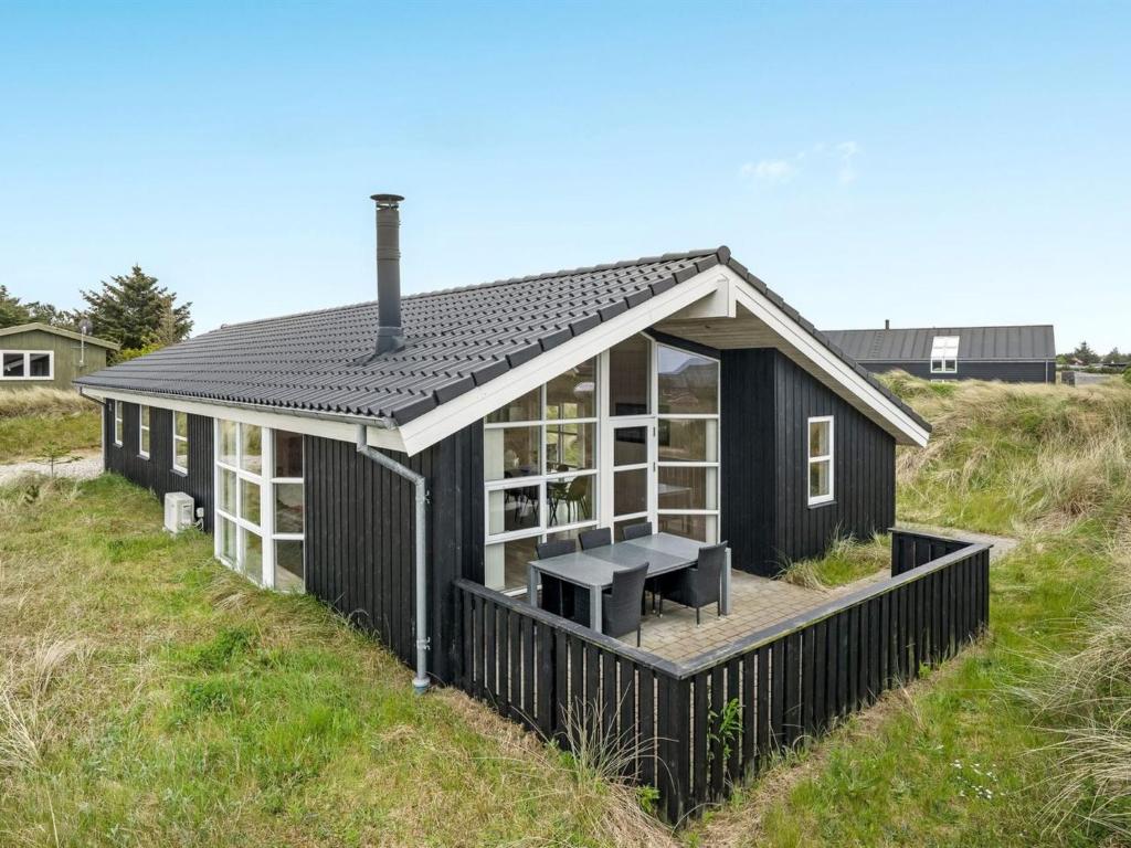 una casa negra en una colina con césped y una mesa de picnic en Holiday Home Frido - 400m from the sea in NW Jutland by Interhome en Torsted