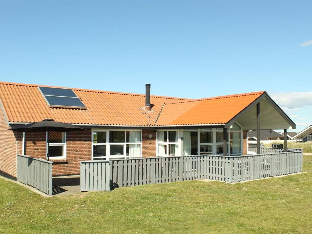 a house with an orange roof and a white fence at Holiday Home Gottfreda - 330m to the inlet in Western Jutland by Interhome in Havrvig