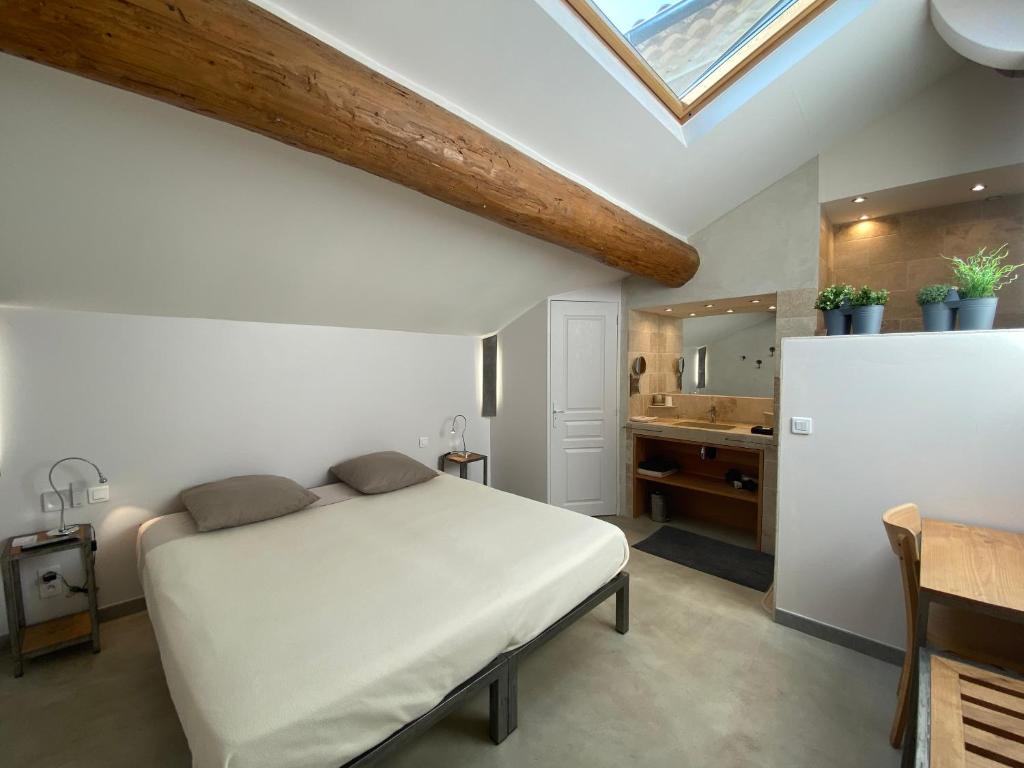 een slaapkamer met een bed en een badkamer met een wastafel bij L'atelier B&B in Bédoin