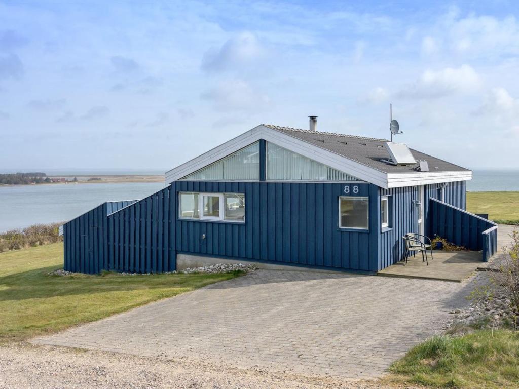 a blue house sitting on top of a beach at Holiday Home Rajna - 95m to the inlet by Interhome in Lemvig