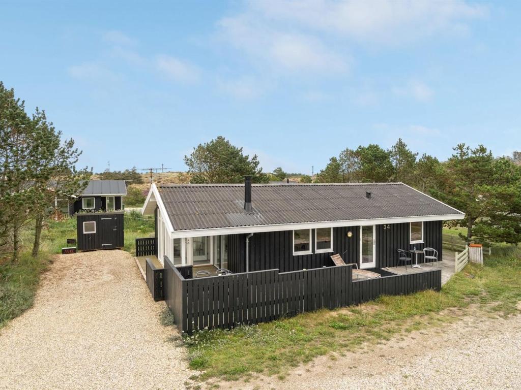 une maison noire et blanche sur une route en gravier dans l'établissement Holiday Home Mads - 950m from the sea in NW Jutland by Interhome, à Torsted