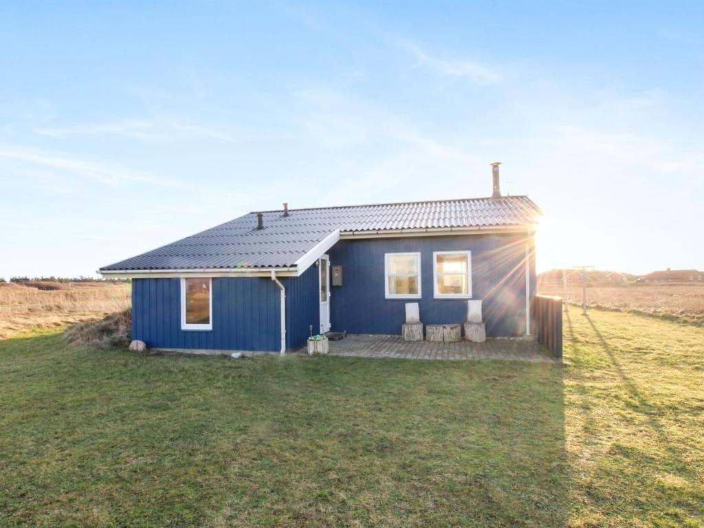 a blue tiny house in a field at Holiday Home Soyala - 400m from the sea in Western Jutland by Interhome in Harboør
