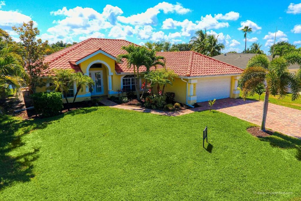 a house with a green lawn in front of it at Casa Nalani - phenomenal 8 guest holiday villa in the Yacht Club in Cape Coral