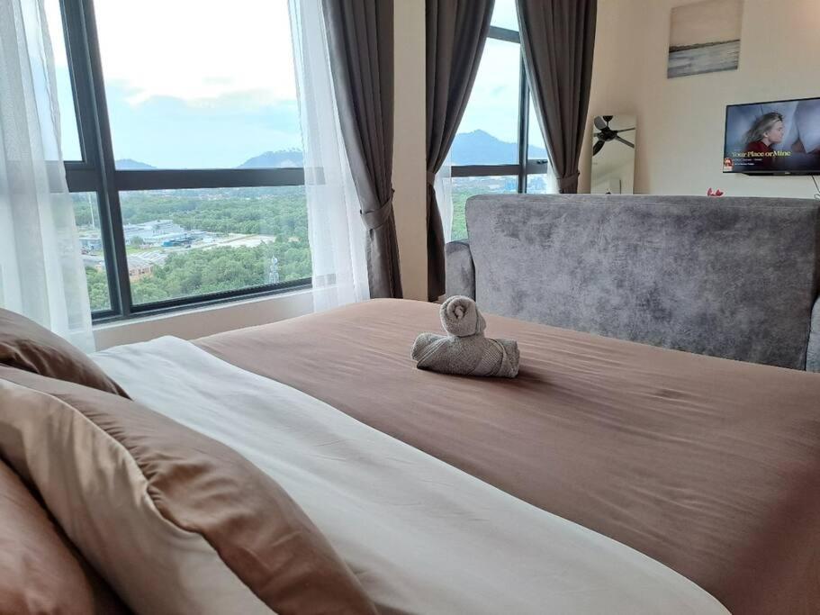 ein ausgestopftes Tier auf einem Bett mit einem großen Fenster in der Unterkunft Best Moments Studio City - Imperium Residence in Kuantan