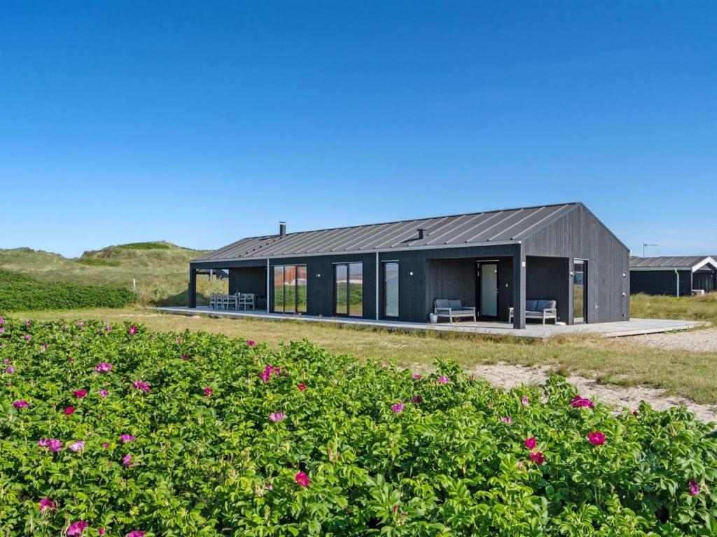 una casa con techo negro en un campo de flores en Holiday Home Aiko - 50m from the sea in NW Jutland by Interhome, en Torsted