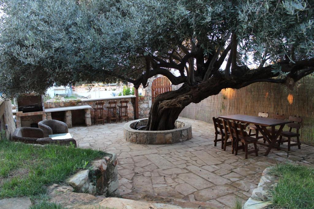 a table and chairs under a tree in a patio at Olive Beach Villa in Peyia