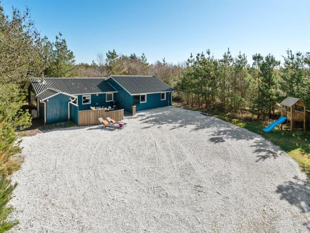 a yard with a blue house and a playground at Holiday Home Anegrete - 900m from the sea in NW Jutland by Interhome in Torsted