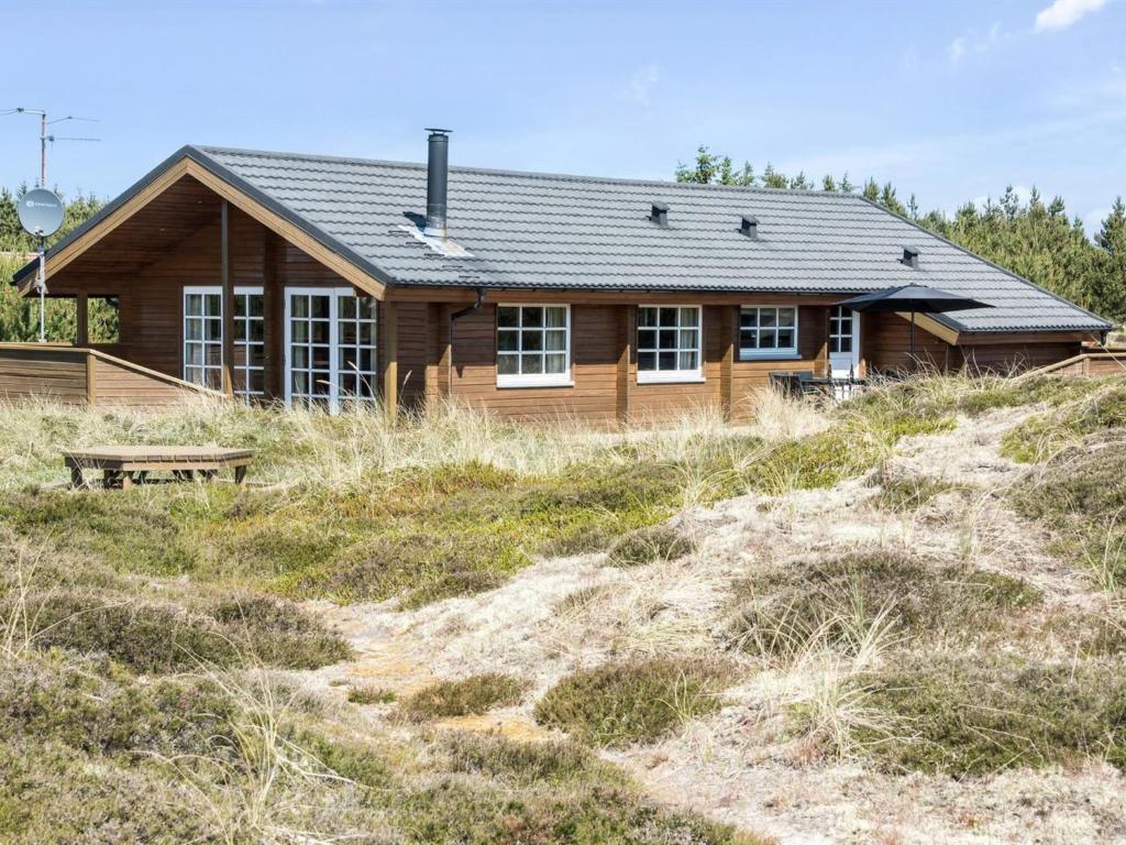 una cabaña de madera en una colina frente a una casa en Holiday Home Eggerich - 900m from the sea in NW Jutland by Interhome, en Torsted