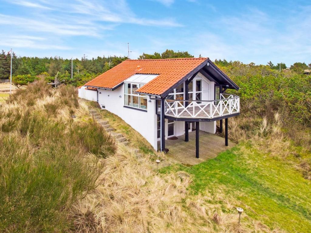 Torsted的住宿－Holiday Home Viktorija - 800m from the sea in NW Jutland by Interhome，山坡上一座白色房子,屋顶橙色