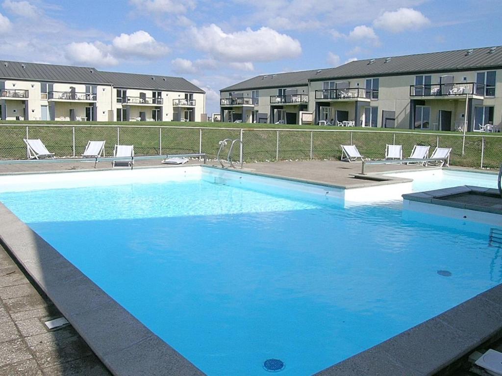uma grande piscina azul em frente a alguns apartamentos em Apartment Tinke - 150m from the sea in NW Jutland by Interhome em Lokken