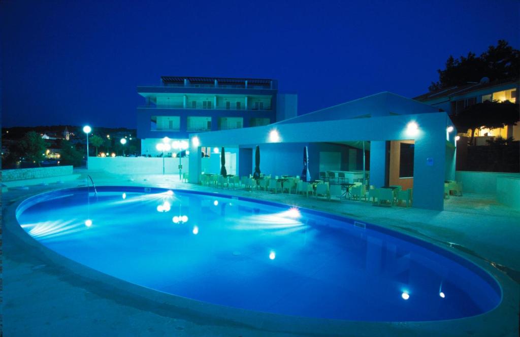 a swimming pool in front of a building at night at Apartments Marija in Postira