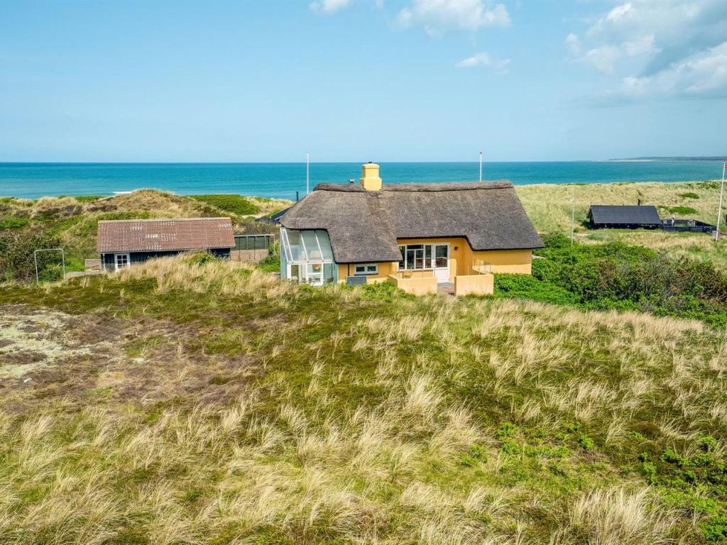 uma casa numa colina com o oceano ao fundo em Holiday Home Quirina - 75m from the sea in NW Jutland by Interhome em Torsted