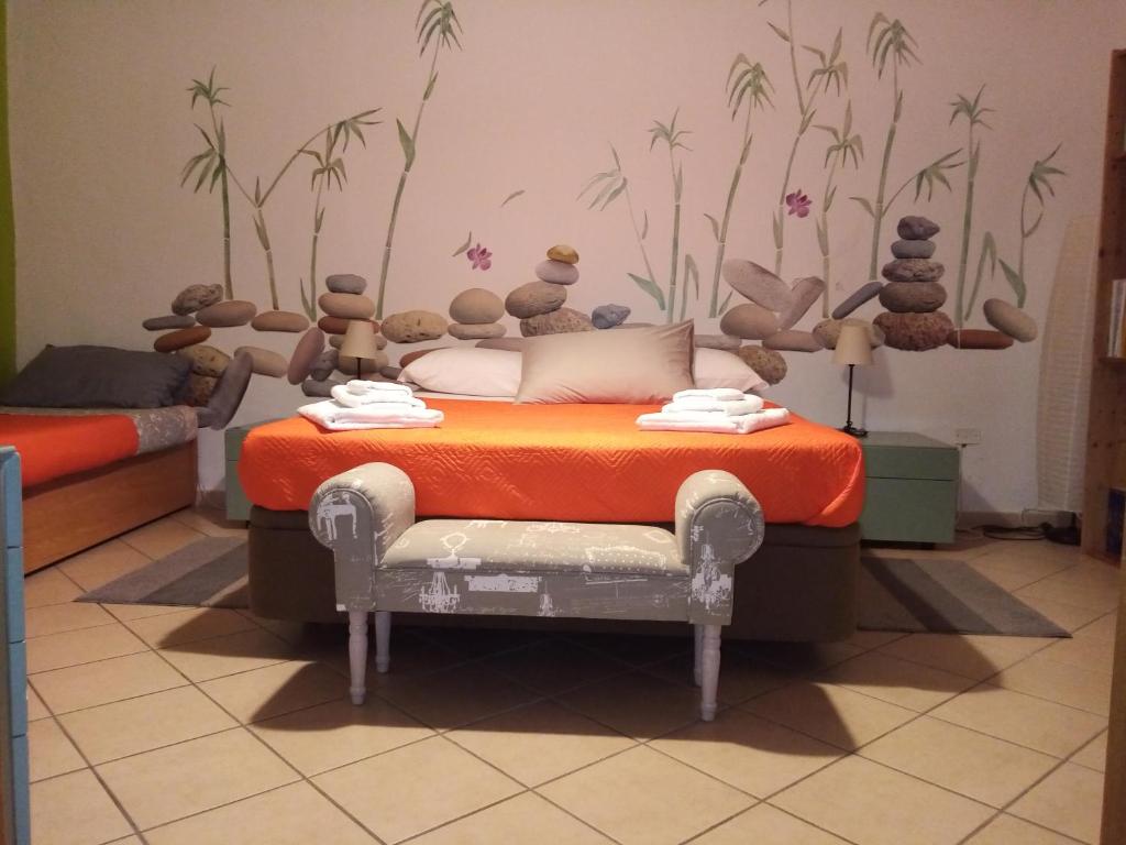 una camera da letto con un letto con una coperta arancione e piante sul muro di Il Nido della Quaglia a Pozzuoli