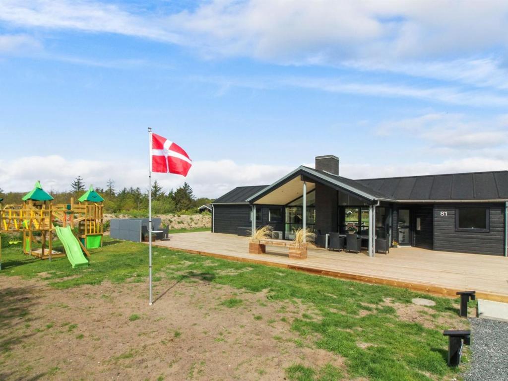 een huis met een speeltuin en een vlag bij Holiday Home Senni - 1-1km from the sea in NW Jutland by Interhome in Løkken
