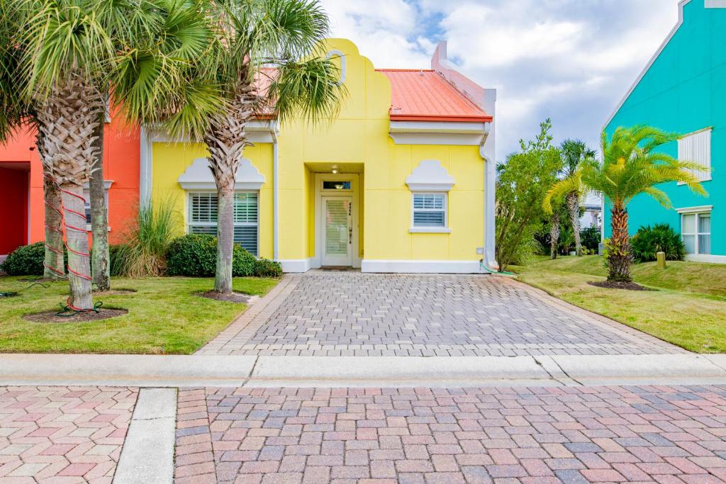 una casa amarilla con palmeras en una entrada en Banana Bay 6056 By Pkrm, en Pensacola