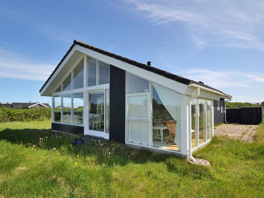 een klein zwart-wit huis in een veld bij Holiday Home Jerker - 400m from the sea in NW Jutland by Interhome in Løkken