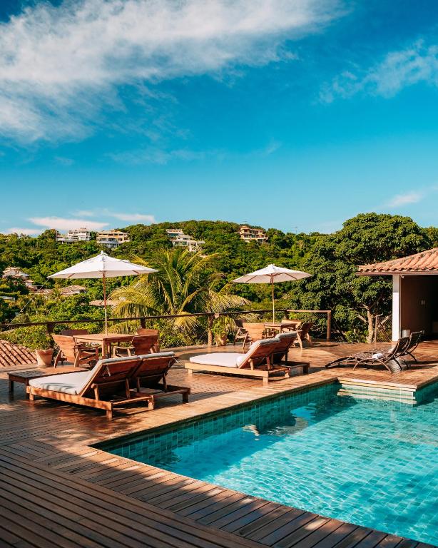 a swimming pool with chairs and umbrellas on a deck at Jubarte Hotel - Tawa Beach Club in Búzios