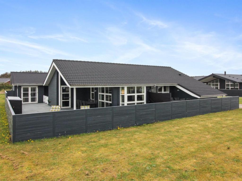 een huis met een zwart hek voor een tuin bij Holiday Home Anett - 400m from the sea in NW Jutland by Interhome in Løkken