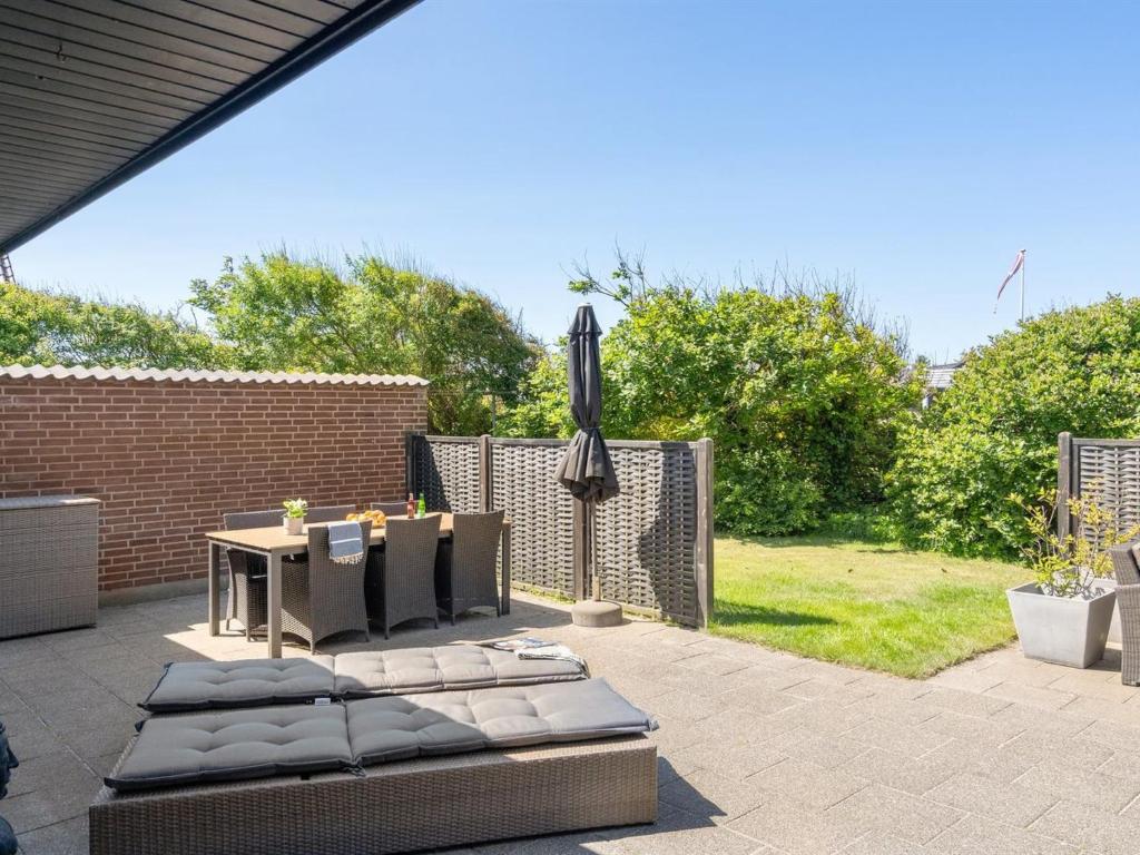 a patio with an umbrella and a table and chairs at Holiday Home Gudlaug - 400m from the sea in NW Jutland by Interhome in Blokhus